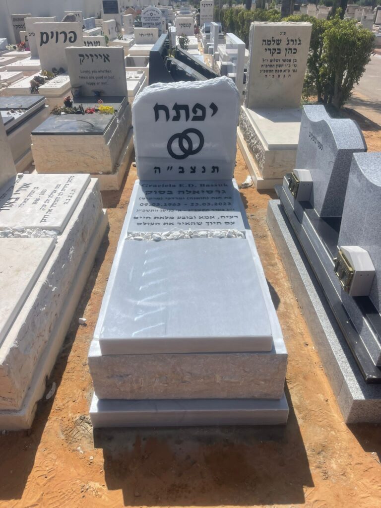 מצבת אבן לבנה עם חיתוך טבעי וכיתוב בעברית בבית עלמין
