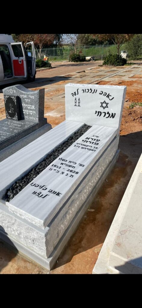 מצבת שיש לבנה מעוצבת עם כיתוב בעברית וכוכב דוד בבית עלמין