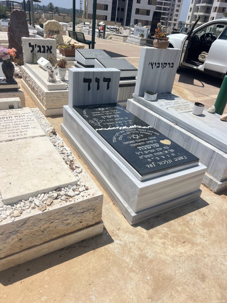 מצבות שיש מודרניות בחלקת קבר בבית העלמין עם כיתוב בעברית