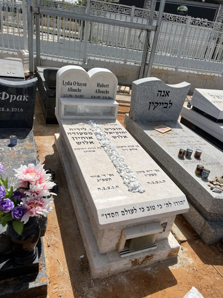 צילום של מספר מצבות מאבן עם כתובות וסלעים בבית עלמין