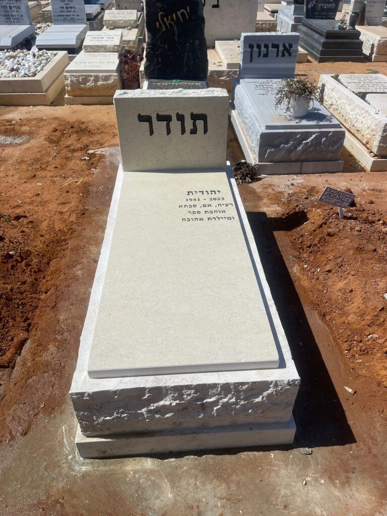 מצבה לבנה חדשה בבית קברות עם חריטה בעברית