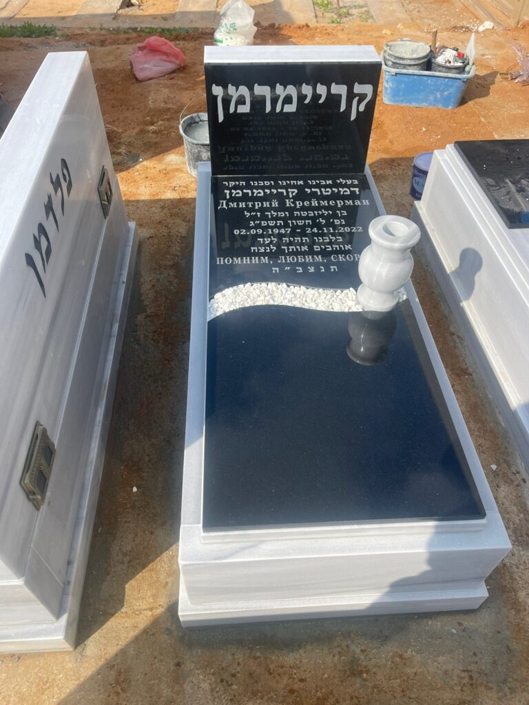 מצבה מסיבית משיש שחור עם חריטות עברית ורוסית בבית עלמין