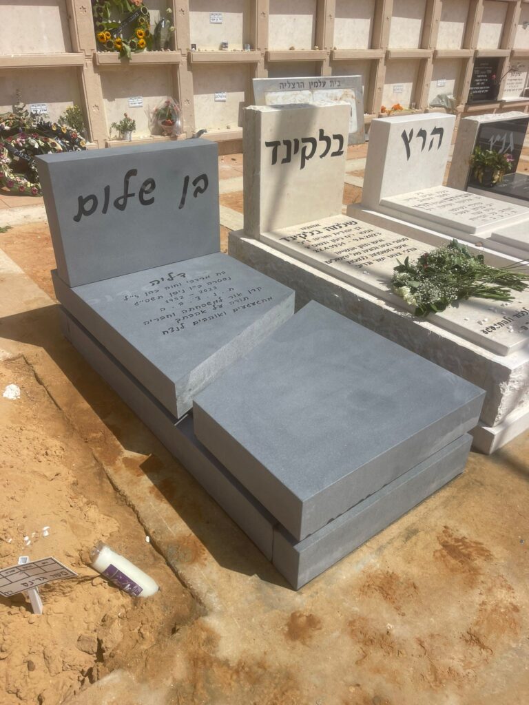 מצבות אבן מודרניות בבית עלמין עם כתובות בעברית וזר פרחים