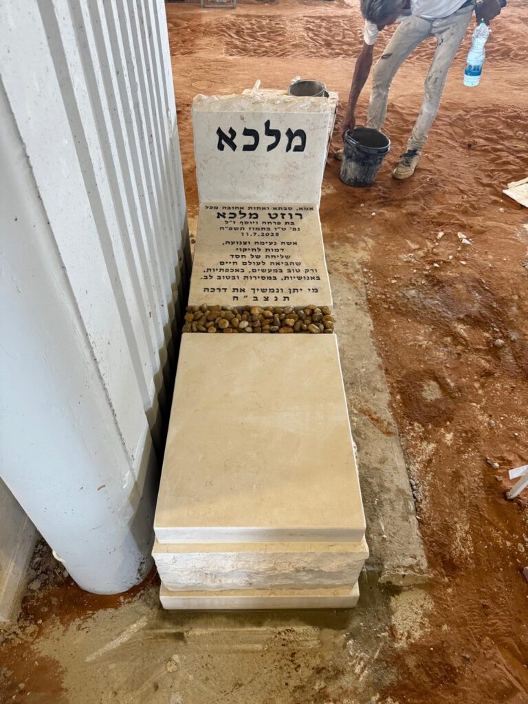 מצבת שיש מעוצבת עם כיתוב בעברית בשלב התקנה בבית עלמין