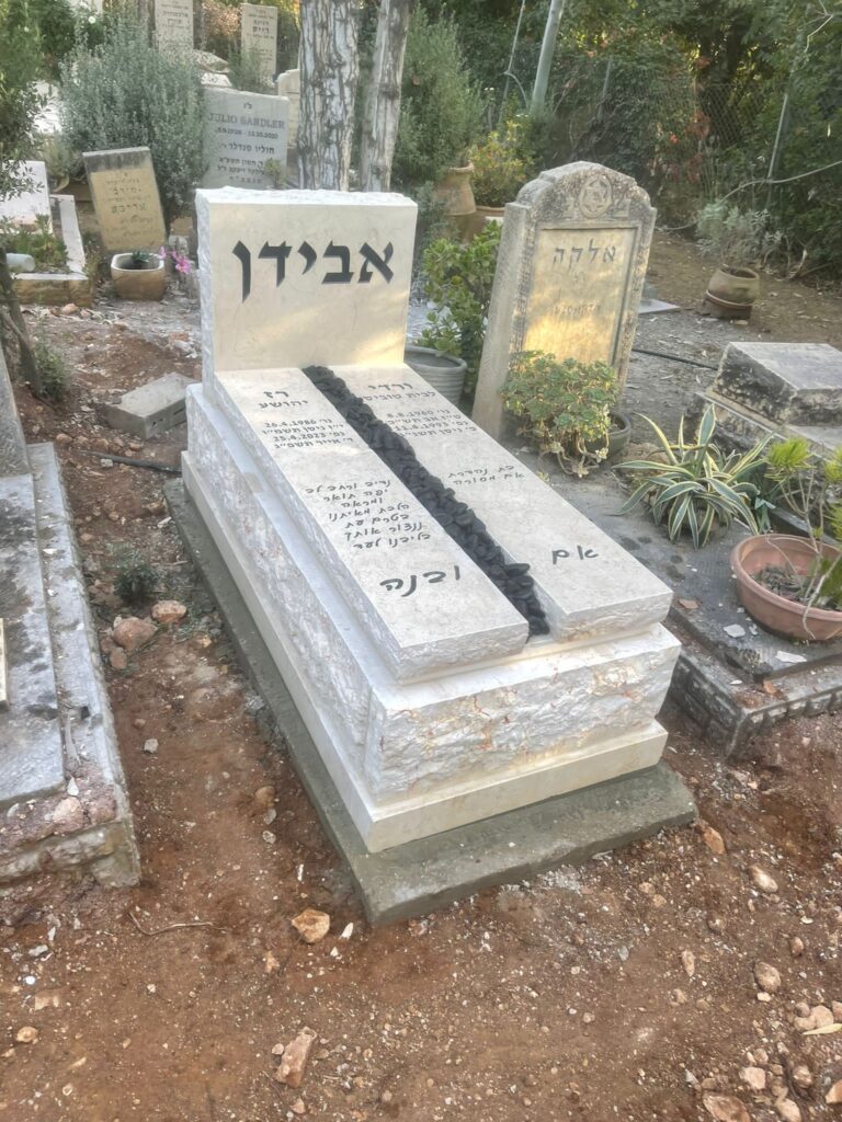 מצבה אבן מעוצבת עם השם 'אבידן' בבית עלמין.