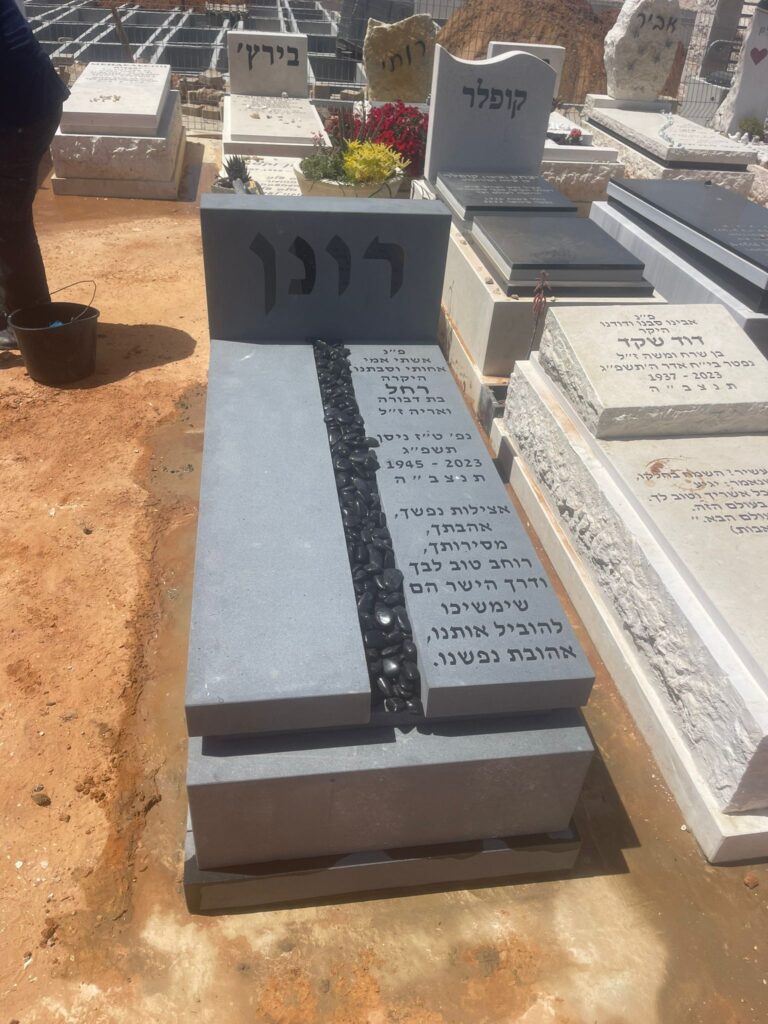 מצבה אפורה מודרנית עם שביל אבנים וכיתוב עברי בבית עלמין